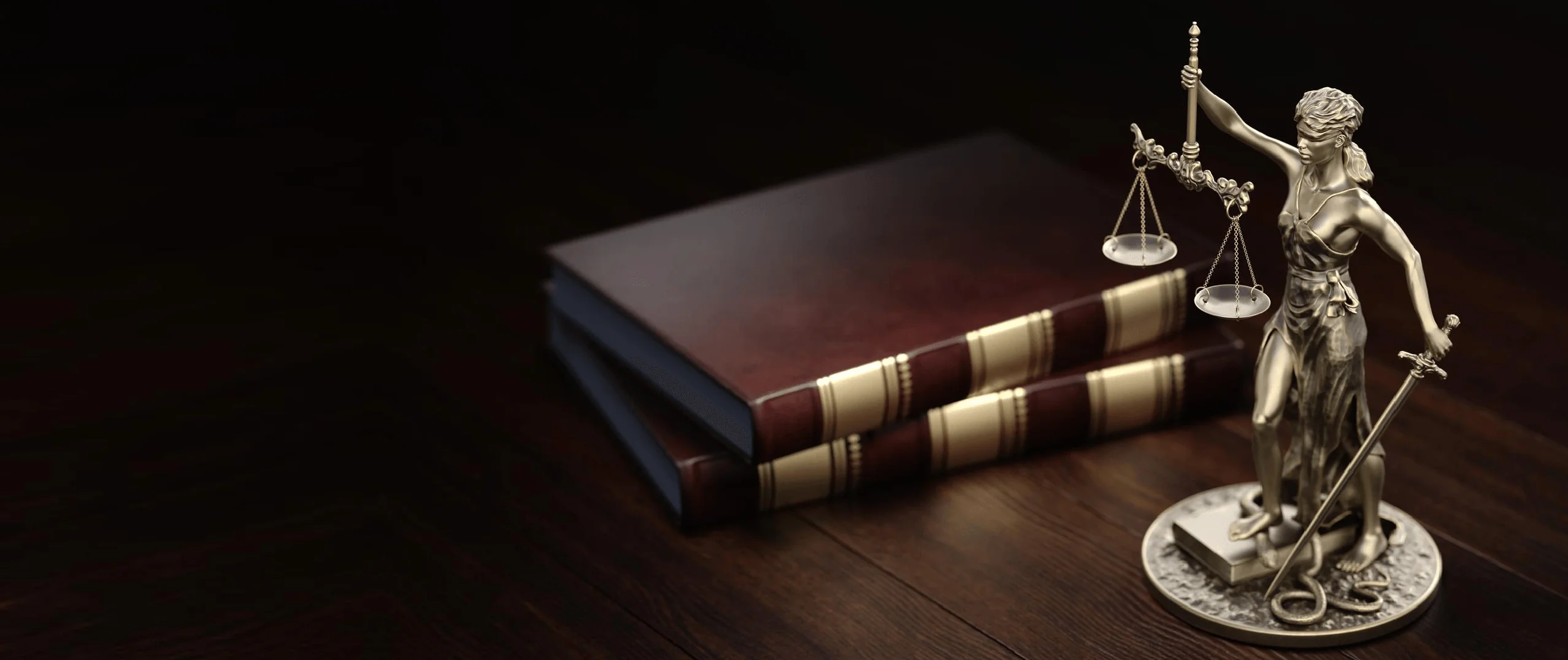 Estátua dourada da Dama da Justiça segurando balança equilibrada, posicionada sobre livros de Direito empilhados em mesa de madeira escura — representação clássica da autoridade jurídica e da tradição do Direito